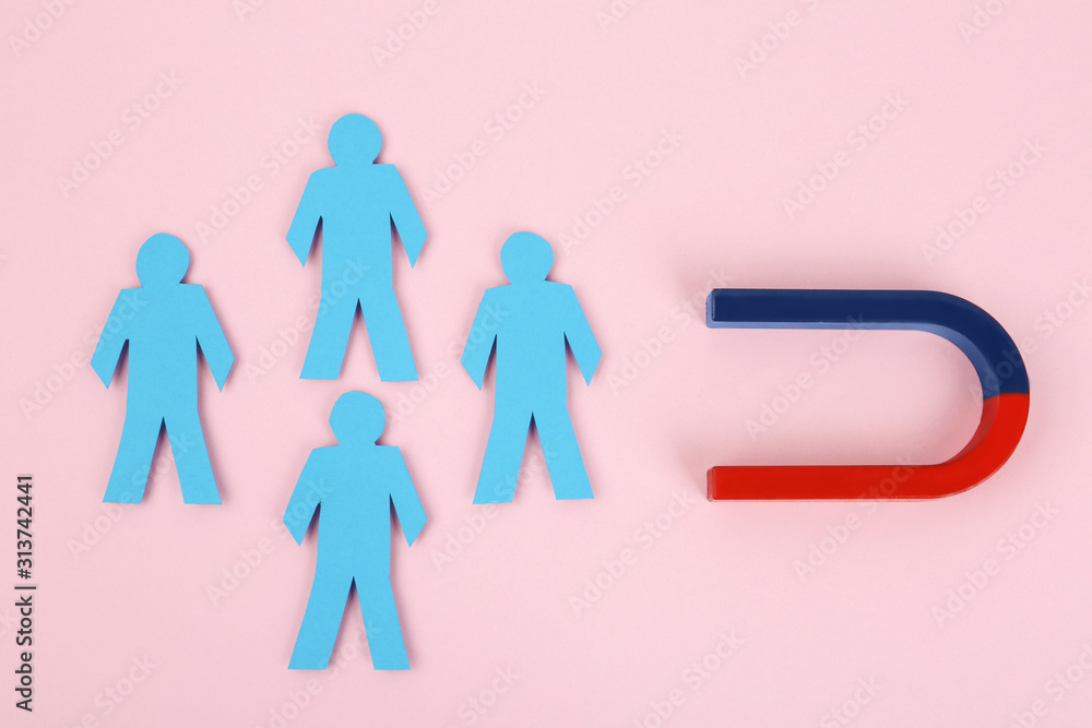 Magnet attracting paper people on pink background, flat lay Magnet attracting paper people on pink background, flat lay
