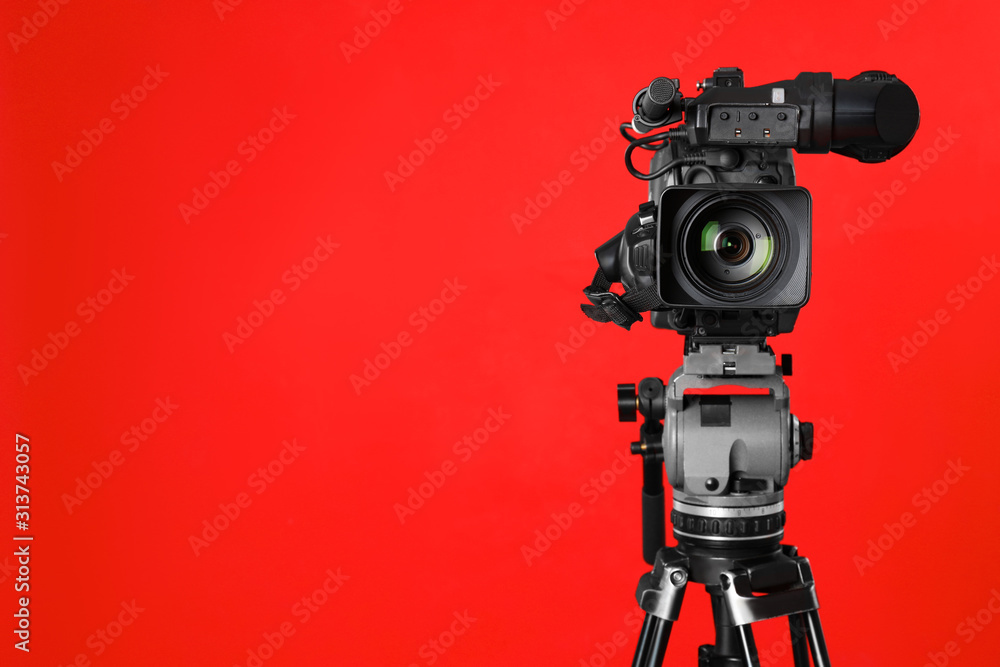 Modern professional video camera on red background. Space for text