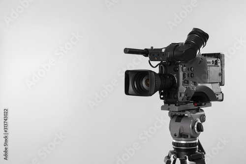 Modern professional video camera on light background. Space for text