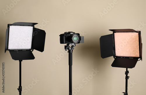 Professional video camera and lighting equipment on beige background photo