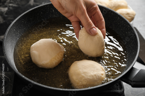 Woman cooking delicious donuts in oil, closeup