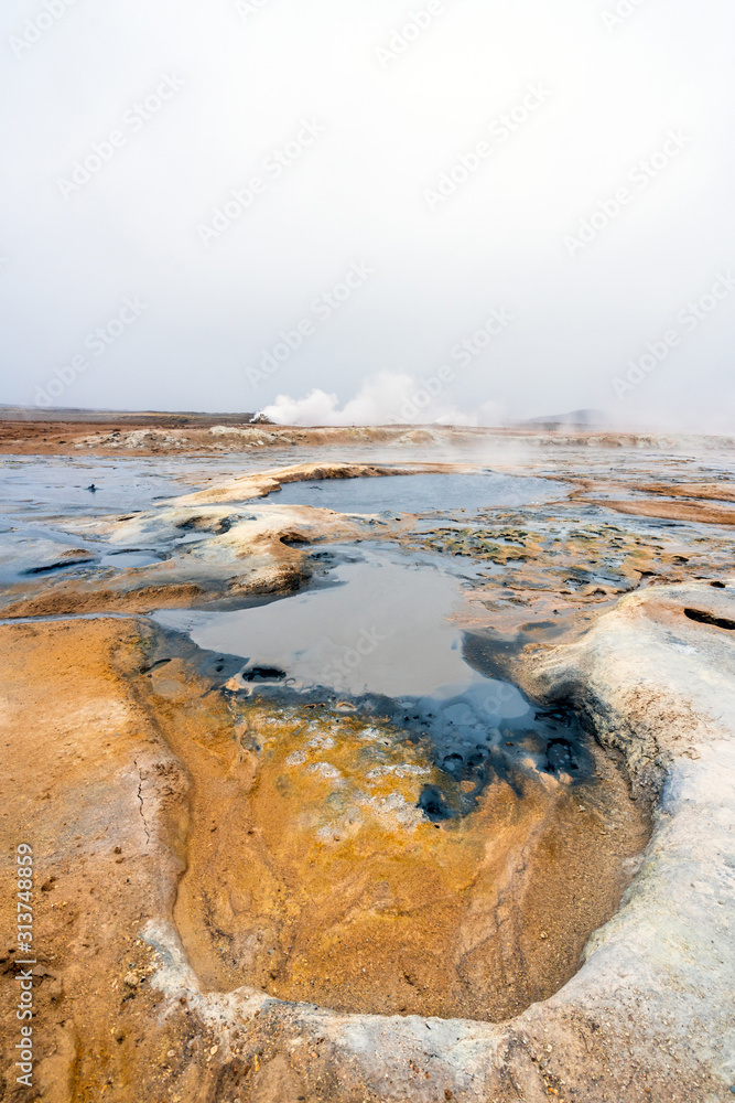Vertical shot of Colorful and textured volcanic ground in geothermal area in Icelandic scenery towards steam vents. Minerals and geology concept. Wallpaper and background theme.