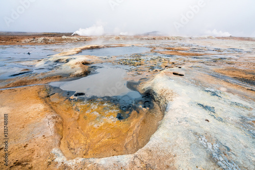 Colorful and textured volcanic ground in geothermal area in Icelandic scenery towards steam vents. Minerals and geology concept. Wallpaper and background theme.