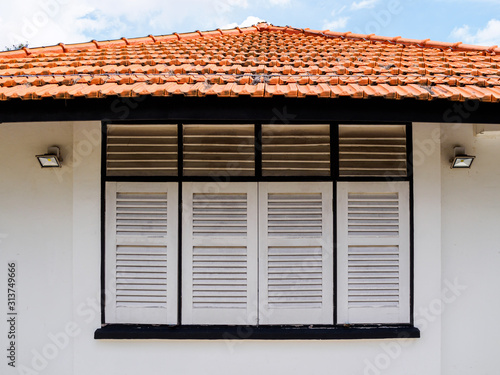 Canvas Print Close up of the antique wooden window shutters and red tiled roof of a whitewash