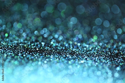 Blue glitter with green bokeh on a black background. Turquoise glitter brilliant mockup.Vibrant background with twinkle lights.blue shiny layout.