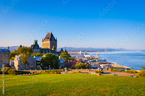 Cityscape view of Old Quebec City with buildings, green grass against St Lawrence river and blue sky in summer evening photo