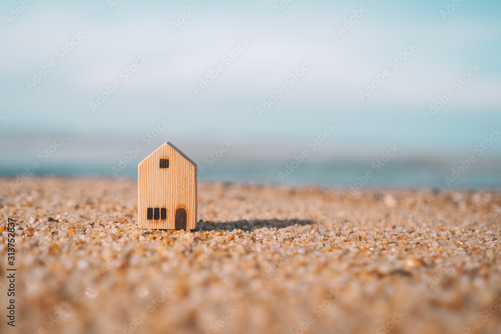 © tonktiti - Small home model on sunset beach sand texture background.