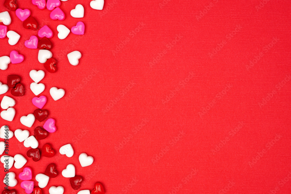 Valentines Day side border of candy hearts over a red textured background. Top view with copy space.
