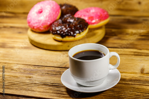 Cup of coffee and tasty donuts on a wooden table