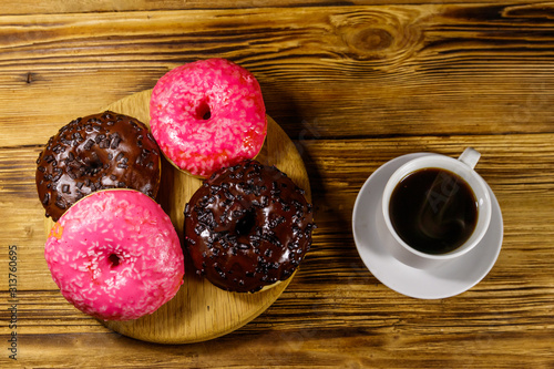 Cup of coffee and tasty donuts on a wooden table. Top view