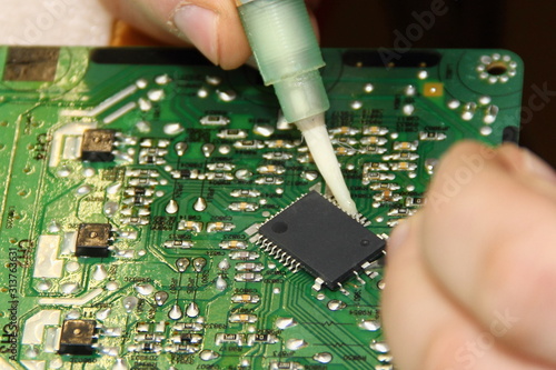 Digital electronics repair, applying flux solder from a syringe to the processor contacts for replacement