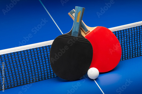 Foto Ping pong rackets and balls on a blue table with net.