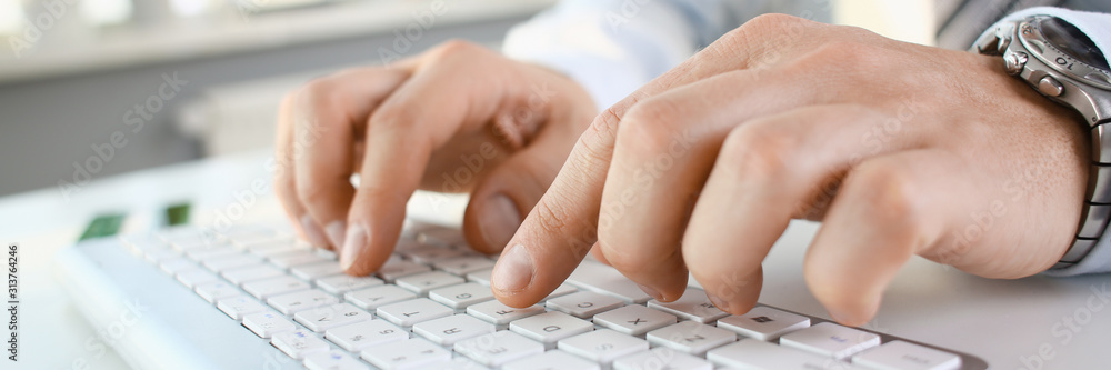 Male arms in suit typing on silver keyboard Male arms in suit typing on silver keyboard