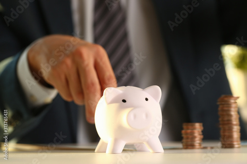 Hand businessman putting pin money into pig
