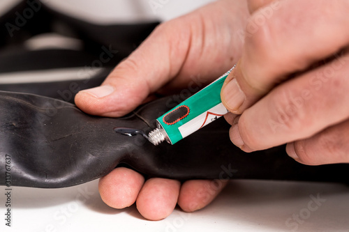 Bicycle inner tube repair. A person is applying adhesive or glue on inner tube before applying a patch for vulcanisation and sealing of the puncture.