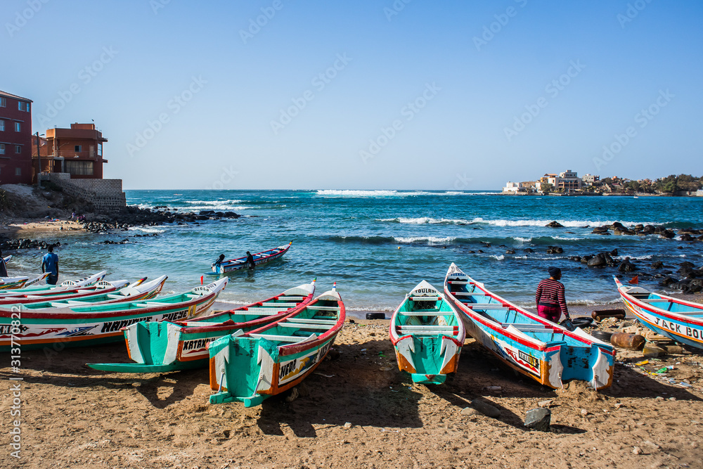 Fishing boats in Ngor Dakar, Senegal, called pirogue or piragua or piraga. Colorful boats used by fishermen standing in the bay of Ngor on a sunny day.