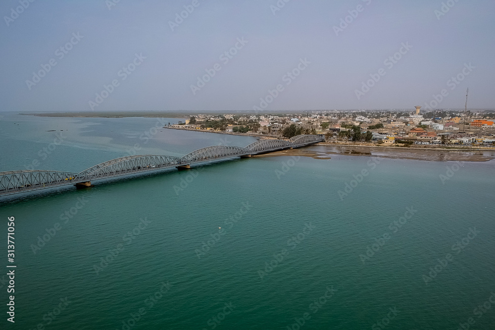 Aerial photo of Senegal river in Sant Louis, Senegal, with the Faidherbe bridge seen connecting the new part of the city on an overcast day.