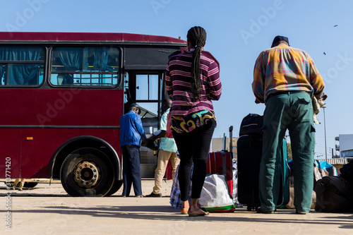 People waiting with luggage to embark on a bus from Dakar to Ziguinchor in Senegal, Africa. Travek with bus in Africa, people standing on a platform in front of a bus. photo