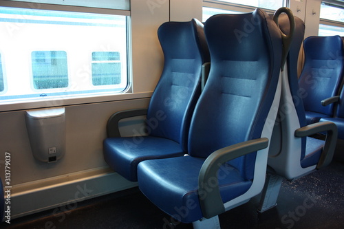 blue lined seats lined up along the corridor of a regional train with no passengers during the day