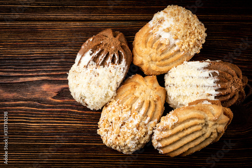 Shortbread cookies with peanut and coconut on dark wooden background.
