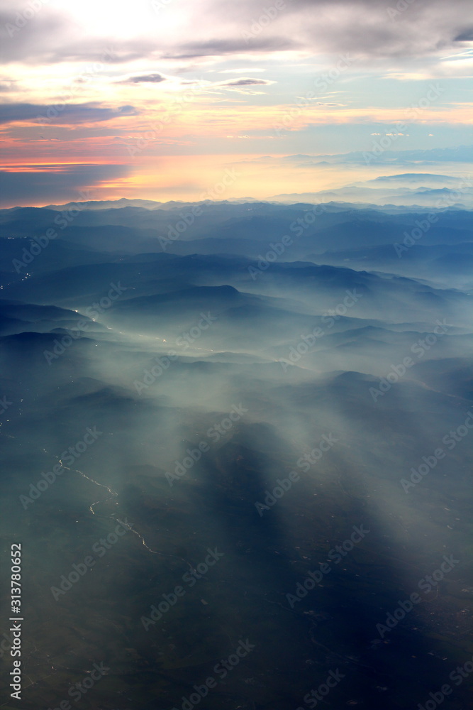 spectacular sunset seen from an airplane with the sun reflecting off a river and the  mountains in the background