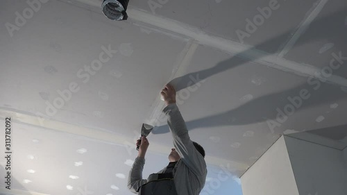 Worker stick glass fiber tape on ceiling gypsum sheets joint