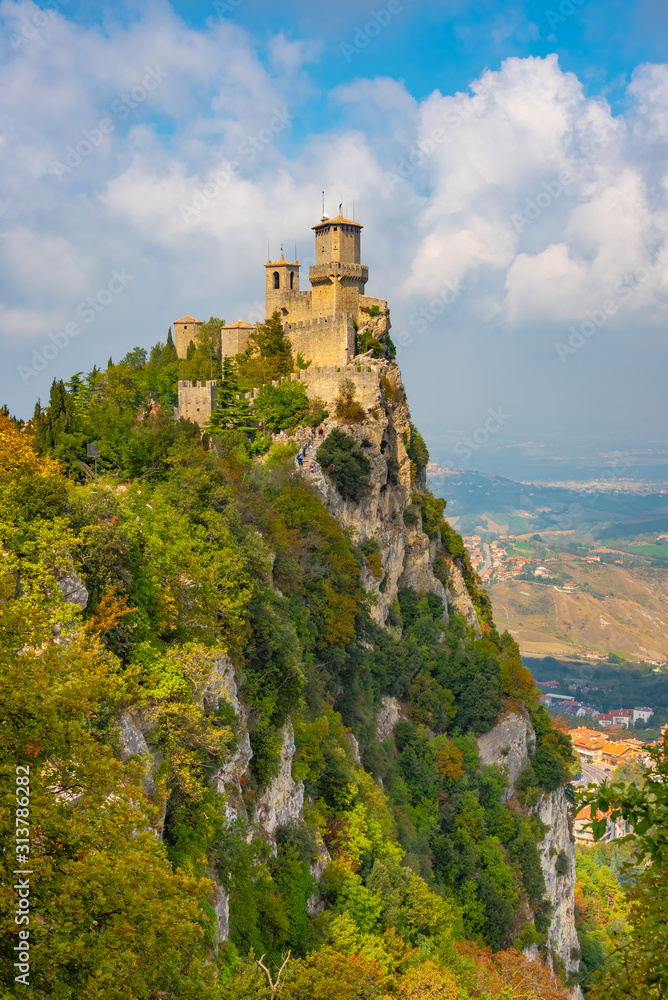 Italy, the Guaita tower in San Marino is illuminated by the bright summer sun, blue sky and clouds.