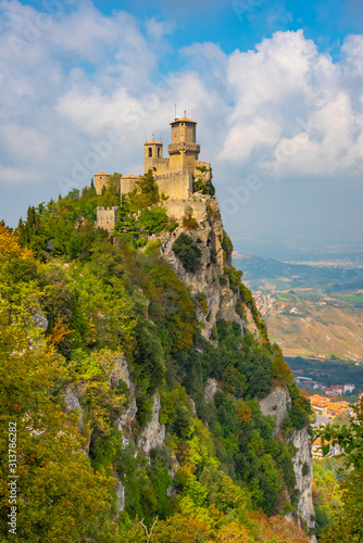 Italy, the Guaita tower in San Marino is illuminated by the bright summer sun, blue sky and clouds.
