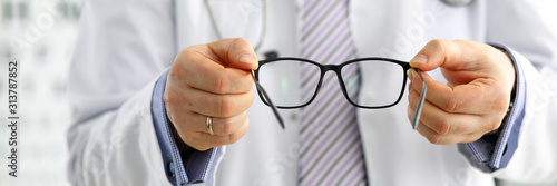 Male medicine doctor hands giving pair of black glasses