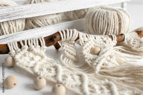 Handmade macrame braiding and cotton threads on rustic wooden stick. Boho image good for macrame and rustic handicrafts banners and advertisement