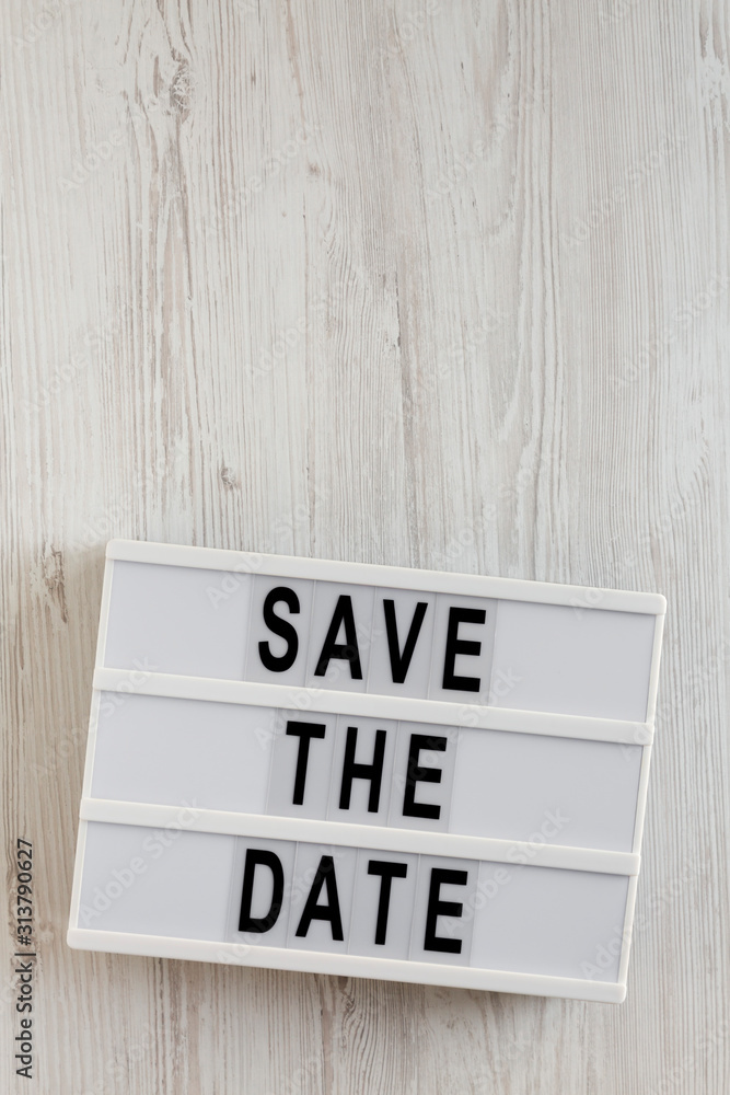 'Save the date' words on a lightbox on a white wooden surface, top view. Overhead, from above, flat lay. Copy space. 'Save the date' words on a lightbox on a white wooden surface, top view. Overhead, from above, flat lay. Copy space.