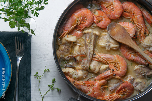 Tableau sur toile Typical Spanish fish Zarzuela served on a wooden table