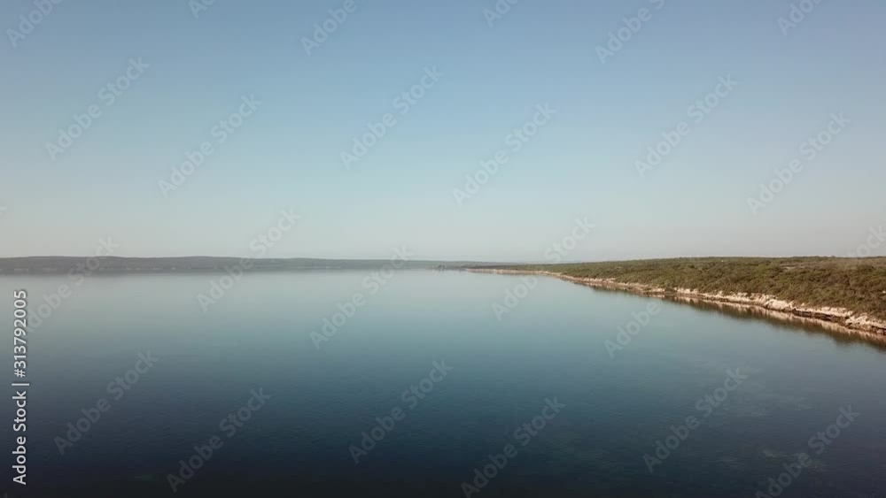 Aerial drone shot of a pristine, glassy calm ocean bay on a sunny, summer day in South Australia. Aerial drone shot of a pristine, glassy calm ocean bay on a sunny, summer day in South Australia.