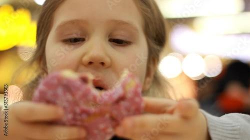 Child eats donut. Closeup baby girl eating doughnut with glase. Delicious, sweet, sweettooth photo