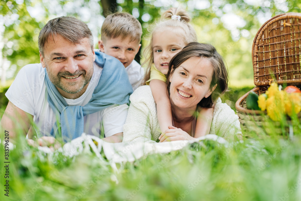 Parents laying on the grass in the park holding their children. Parents laying on the grass in the park holding their children.