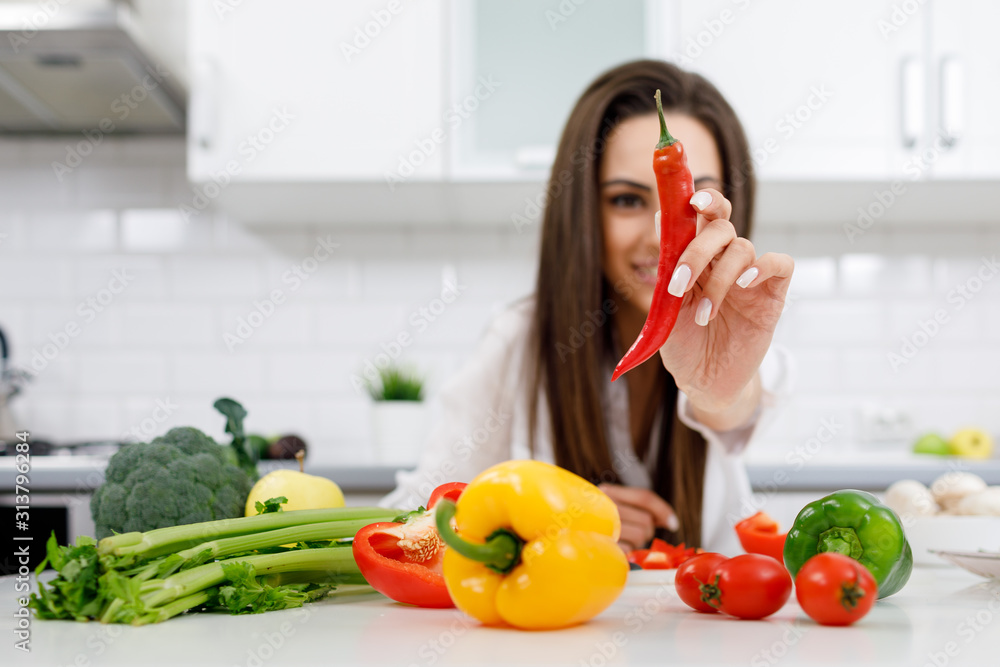Close-up of a chili pepper demonstrated to camera by blurred young brunette Close-up of a chili pepper demonstrated to camera by blurred young brunette