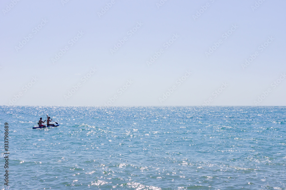 Two men swimming on a long board in the sea or ocean in a sunny day. Surfing and vacation concept.