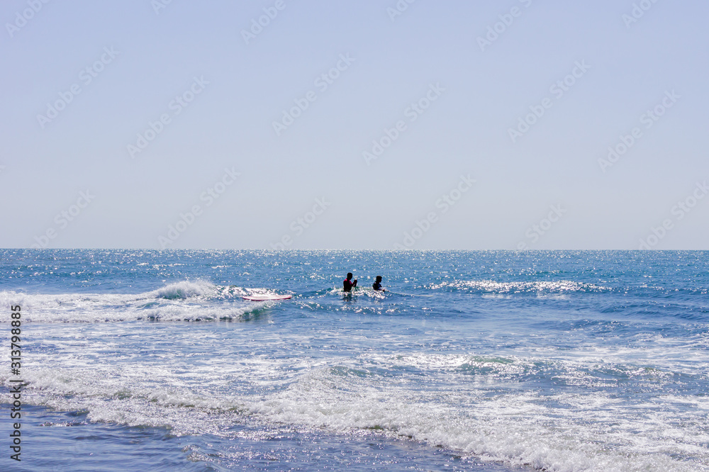Two men swimming on a surf board in the sea or ocean in a sunny day. Surfing and vacation concept.