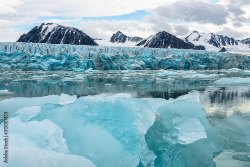 Gletscher mit blauem Eis spiegelt sich im Meer, Berge im Hintergrund