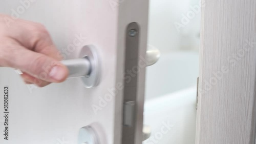 Female hand opens the door in the white bathroom. Close up.