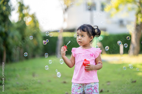 Cute little girl playing with bubbles in park. 