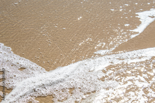 Espuma da onda do mar e areia em dia de sol