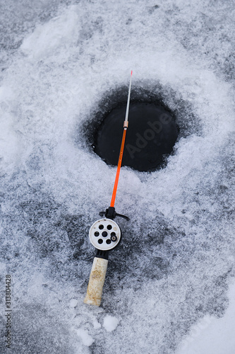 Winter fishing rod at drilled hole catches fish