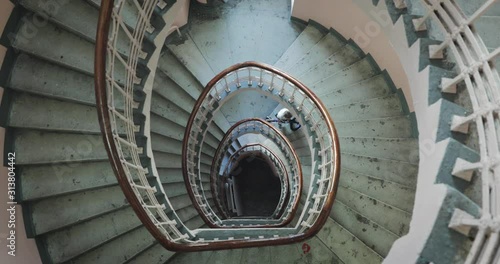 A top view of a spiral staircase with a boy lifting his bicycle in the middle of it