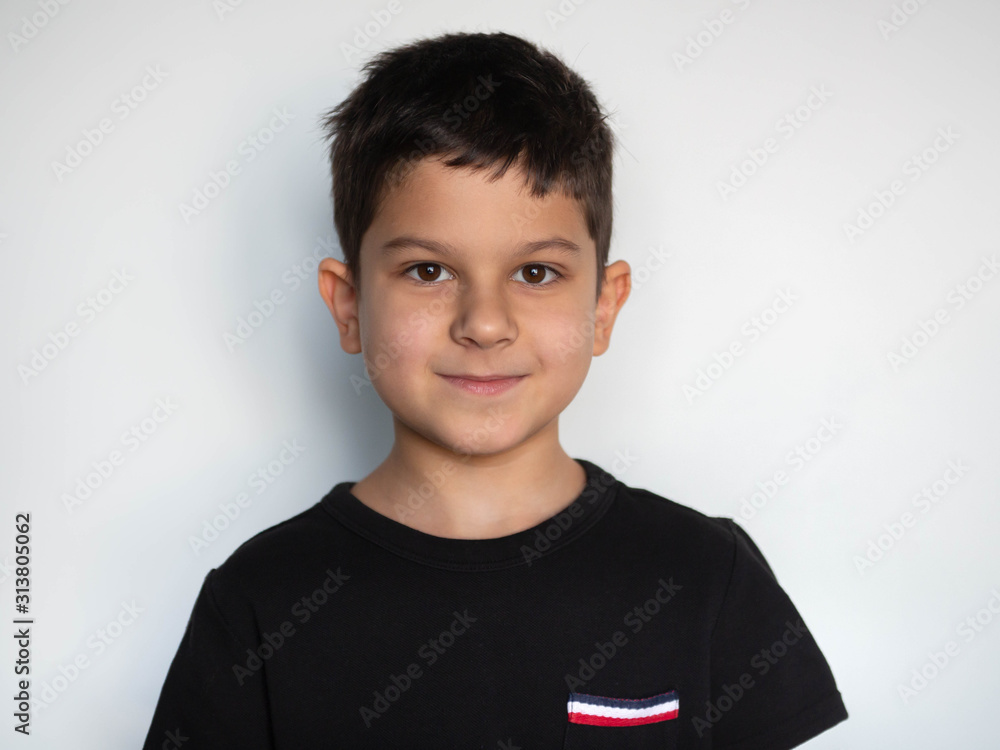 close-up portrait of a small handsome smiling boy in a black T-shirt, isolated on a white background