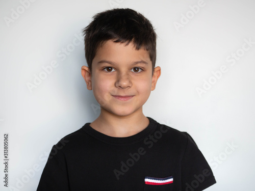 close-up portrait of a small handsome smiling boy in a black T-shirt, isolated on a white background