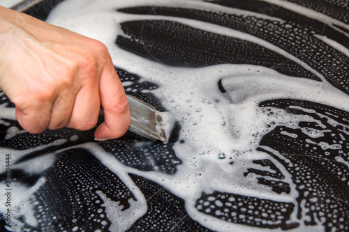 A woman cleans the electronic ceramic hob, using special steel scraper and detergent agent, applied to the surface of the hob. Chores and domestic labour concept.