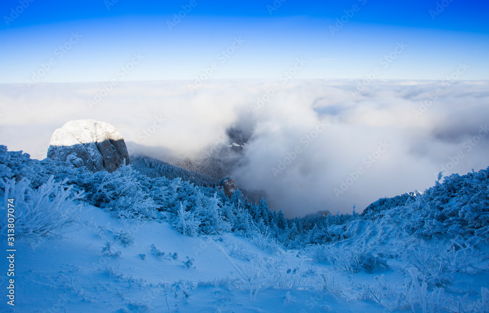 Ceahlau mountain above the clouds sea in winter landscape. Romania