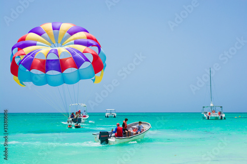 Boats and colorful parasail wing taking off from turquoise water of Sargasso Sea, Punta Cana, Dominican Republic photo