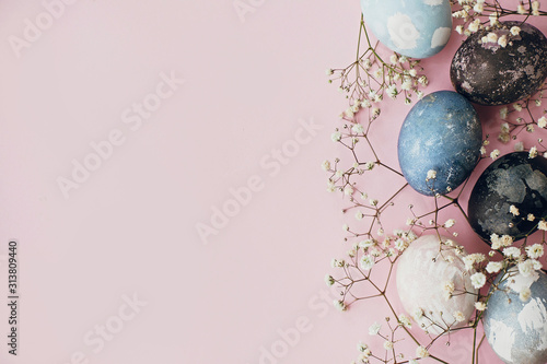 Wallpaper Mural Stylish easter eggs and spring flowers border on pink paper flat lay, space for text